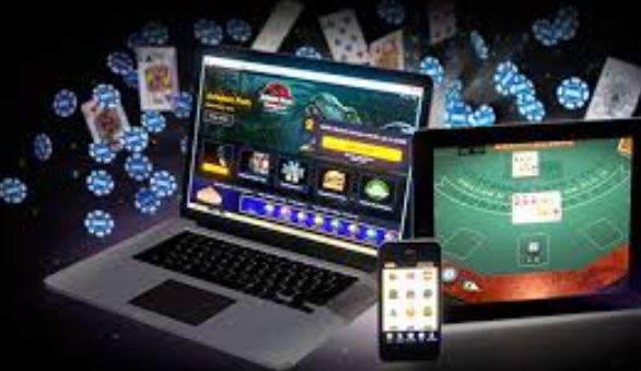 En laptop, en mobiltelefon och en surfplatta omgivna av spelmarker och spelkort.
